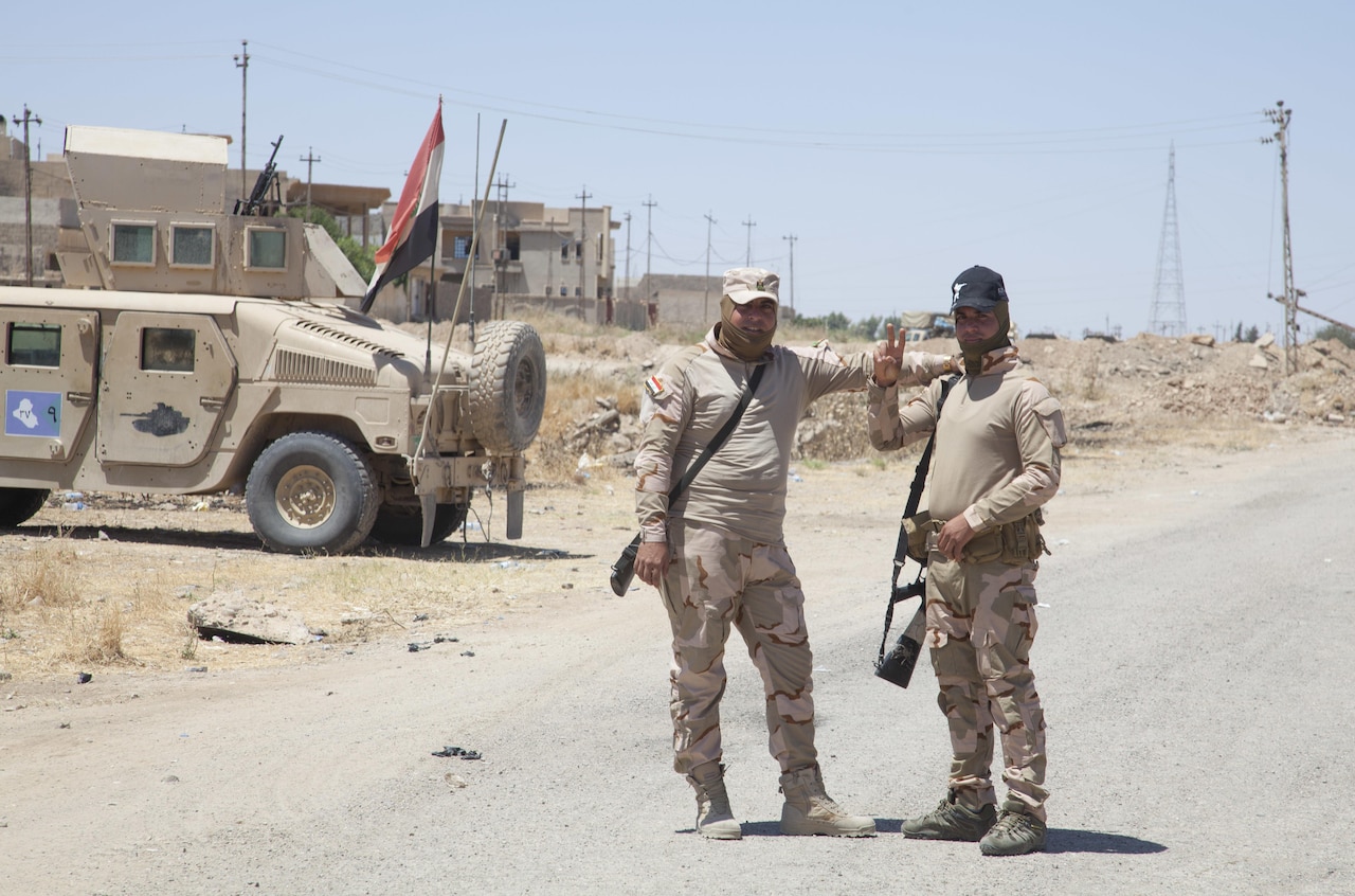 Iraqi soldiers pose for a photo after greeting a convoy of coalition forces in Mosul, Iraq, May 25, 2017. Army photo by Cpl. Rachel Diehm