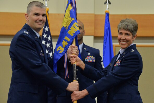 Lt. Col. Deborah Davidson, right, accepts command of the 341st Medical Operations Squadron from Col. Craig Forcum, 341st Medical Group commander, during a change of command ceremony at the Malmstrom Air Force Base Grizzly Bend June 20, 2017. Master Sgt. Kamau Joseph, 341st MDOS superintendent, looks on. (U.S. Air Force photo/Airman 1st Class Daniel Brosam)