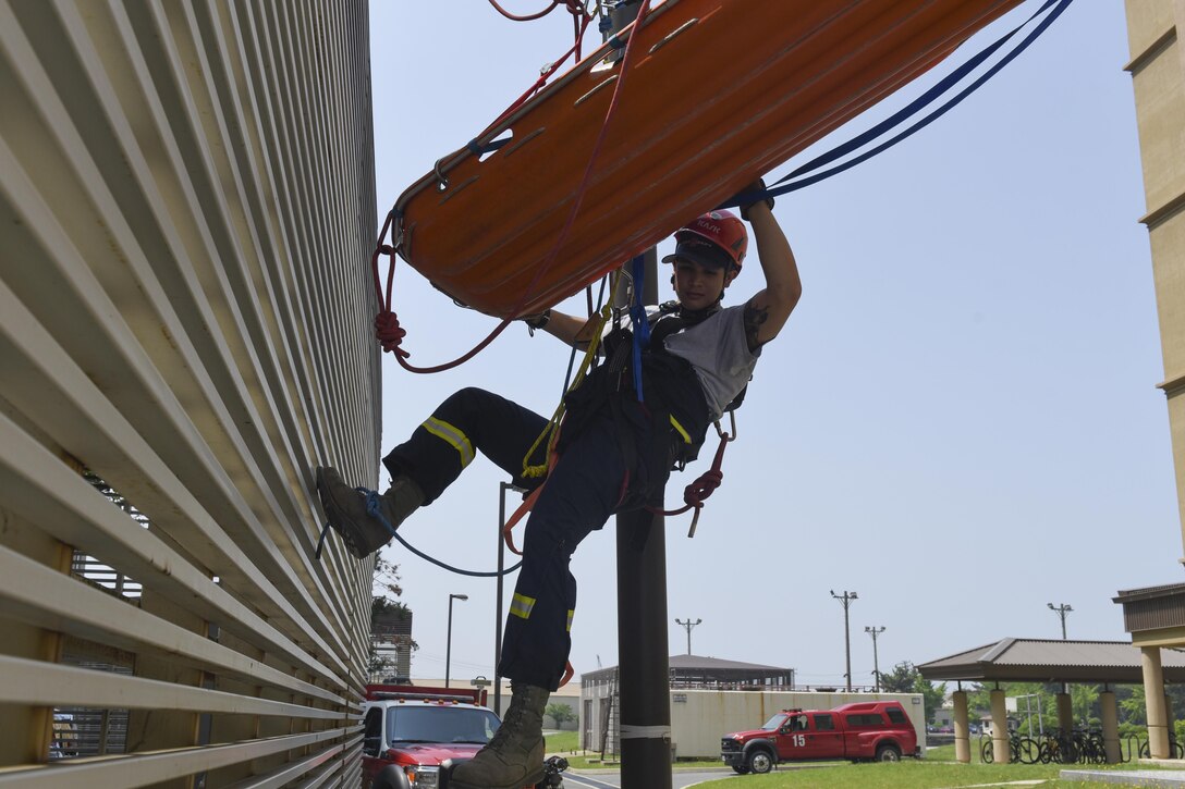 U.S. Air Force Senior Airman Donavin Apiag, 8th Civil Engineer Squadron fire emergency services driver/operator escorts a simulated victim being lowered by firefighters in a Stokes basket during training at Kunsan Air Base, Republic of Korea, June 8, 2017. Apiag participated in the Department of Defense Technical Rescue Course which taught students from the Pacific Air Forces region high and low angle, confined space, and technical rope rescues. (U.S. Air Force photo by Senior Airman Michael Hunsaker/Released)