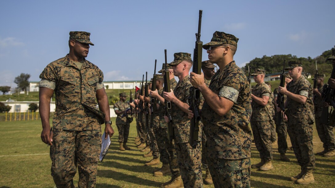 U.S. Marine Corps SSgt. Van Black, with Headquarters Battalion, 3d Marine Division, inspects Marines on their close order drill during a drill competition at the Courtney Bowl on Camp Courtney, Okinawa, Japan, March 31, 2017. Headquarters Company, Truck Company, and Communications Company engaged in a competition against each other for a drill trophy and to aid in preparation for an upcoming commanding general inspection.  (U.S. Marine Corps photo by MCIPAC Combat Camera Lance Cpl.  Jesus McCloud)