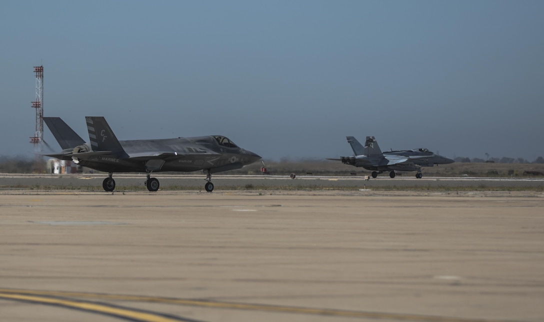 An F-35B Lightning II with Marine Fighter Attack Squadron 211 taxis on the flightline while an F/A-18 Hornet takes off during the Marine Division Tactics Course at Marine Corps Air Station Miramar, Calif., June 16. This course gives pilots air-to-air combat experience and the tools to train Marines in their squadrons on the latest tactics. 