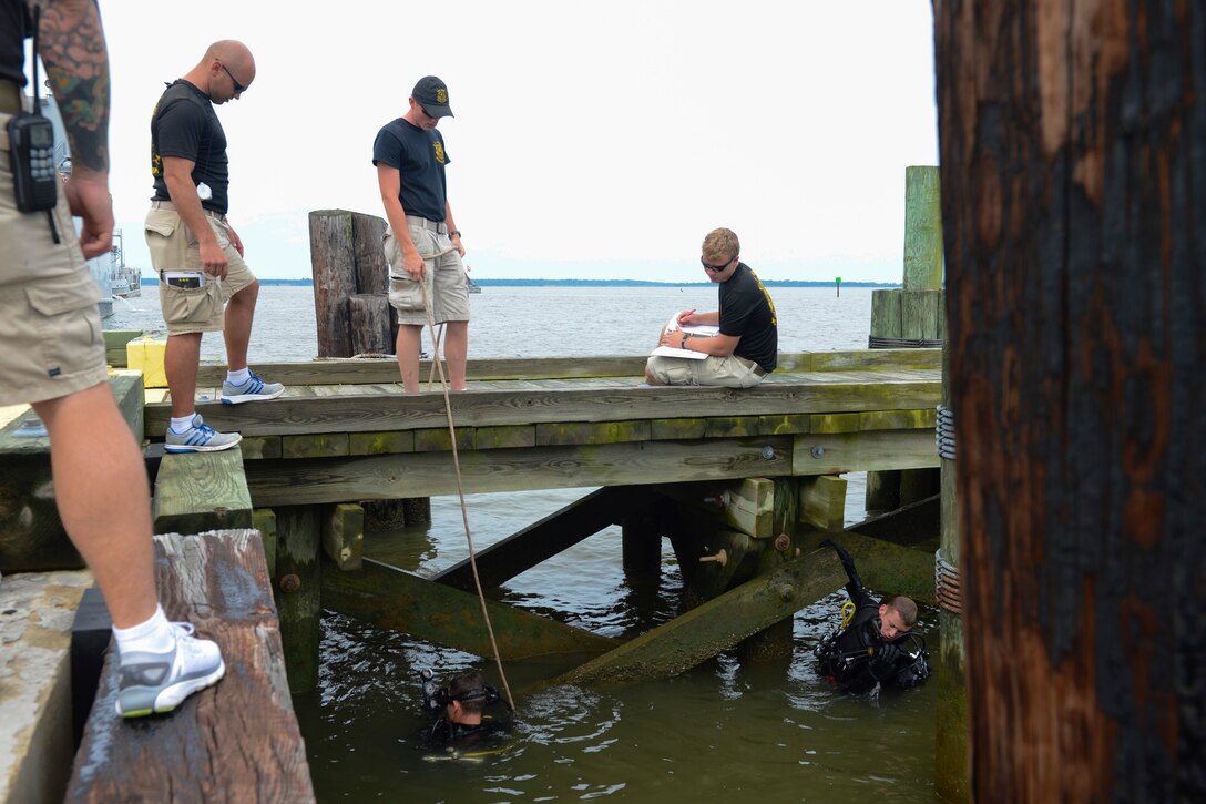 U.S. Army divers assigned to the 74th Engineer Dive Detachment, 92nd Eng. Battalion report their findings while inspecting Third Port’s piers during a diving mission at Joint Base Langley-Eustis, Va., June 20, 2017. While inspecting the piers, the divers will determine if the team has the resources to fix the damage or if they will have to contract out the work. (U.S. Air Force photo/Airman 1st Class Kaylee Dubois)