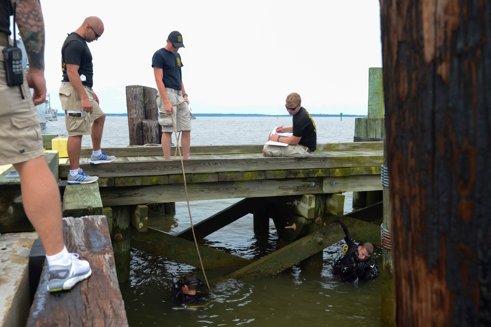 U.S. Army divers assigned to the 74th Engineer Dive Detachment, 92nd Eng. Battalion report their findings while inspecting Third Port’s piers during a diving mission at Joint Base Langley-Eustis, Va., June 20, 2017. While inspecting the piers, the divers will determine if the team has the resources to fix the damage or if they will have to contract out the work. (U.S. Air Force photo/Airman 1st Class Kaylee Dubois)