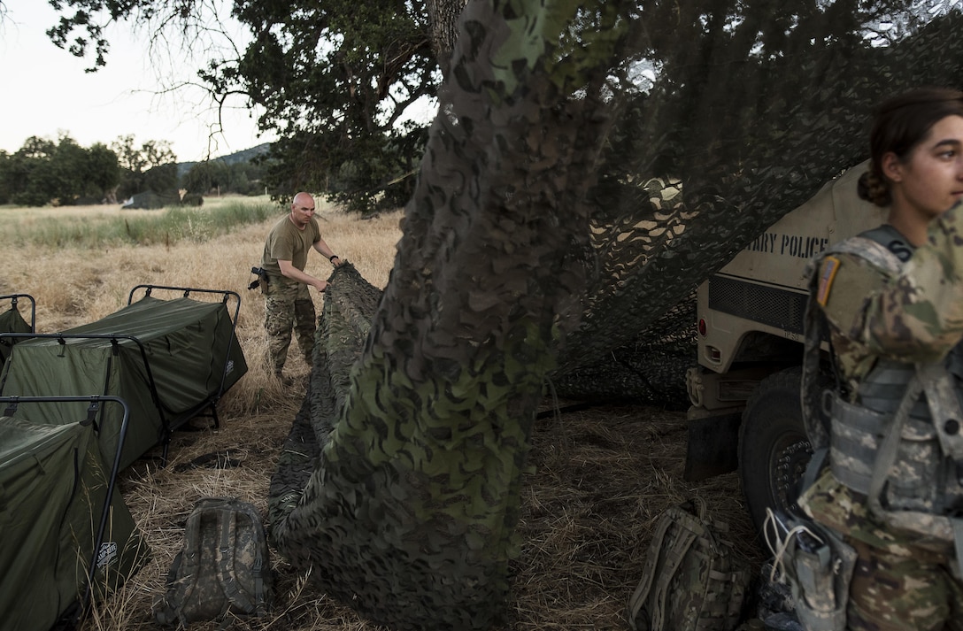 Sgt. Derek Glaspie, of Washington, Iowa, a U.S. Army Reserve military police Soldier with the 339th Military Police Company (Combat Support), headquartered in Davenport, Iowa, works with his team to assemble a camouflage netting system to provide concealment and shade during a Warrior Exercise (WAREX) held at Fort Hunter Liggett, California, June 19. The MP company's Soldiers had to relocate their tactical assembly areas in the field multiple times as they reconnoitered different areas of their operational environment, while fighting against temperatures reaching 100-plus degrees daily. (U.S. Army Reserve photo by Master Sgt. Michel Sauret)