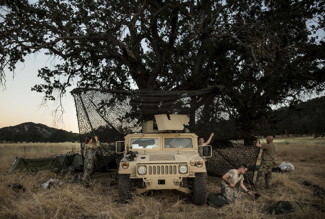 U.S. Army Reserve military police Soldiers from the 339th Military Police Company (Combat Support), headquartered in Davenport, Iowa, assemble a camouflage netting system to provide concealment and shade during a Warrior Exercise (WAREX) held at Fort Hunter Liggett, California, June 19. The MP company's Soldiers had to relocate their tactical assembly areas in the field multiple times as they reconnoitered different areas of their operational environment, while fighting against temperatures reaching 100-plus degrees daily. (U.S. Army Reserve photo by Master Sgt. Michel Sauret)