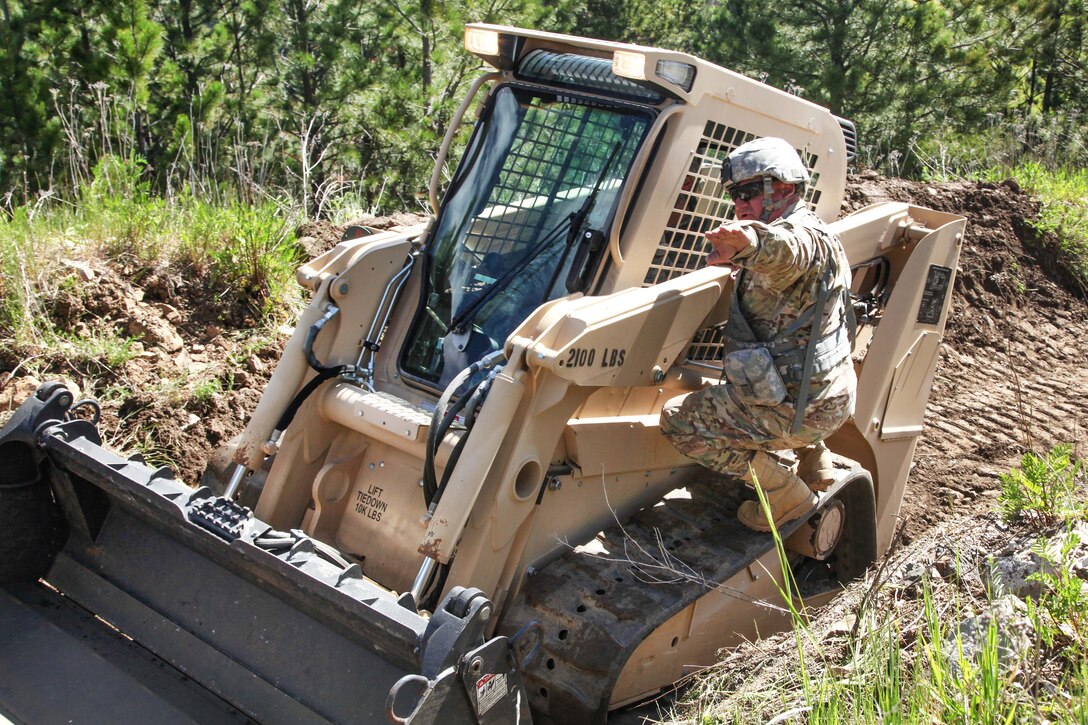 South Dakota Army National Guard Sgt. 1st Class Ron Roselles, right, instructs Spc. Seth Davis as he uses a skid steer to move dirt to make room for transportation pathways in support of Golden Coyote, Lead, S.D., June 14, 2017. Roselles and Davis are assigned to the 842nd Engineer Company. Army photo by Spc. Jeffery Harris