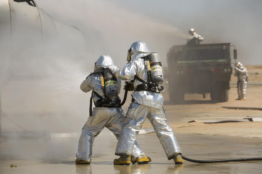 Marines with Air Operation Company, Marine Wing Support Squadron 471, 4th Marine Aircraft Wing, Marine Forces Reserve, extinguish a fire during Integrated Training Exercise 4-17 on Marine Corps Air-Ground  Center, Twentynine Palms, California, June 19, 2017. The exercise trained expeditionary firefighting and rescue Marines so they could gain experience in aircraft  crash fire procedures.
