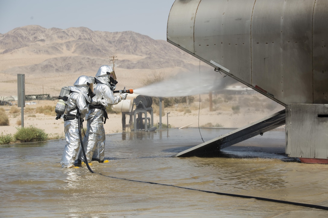 Marines with Air Operation Company, Marine Wing Support Squadron 471, 4th Marine Aircraft Wing, Marine Forces Reserve, approach the rear of burning aircraft during Integrated Training Exercise 4-17 on Marine Corps Air-Ground Center, Twentynine Palms, California, June 19, 2017. The exercise trained expeditionary firefighting and rescue Marines so they could gain experience in aircraft crash fire procedures.