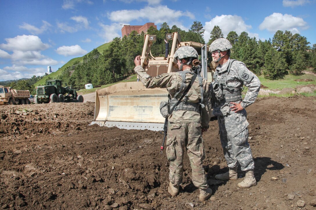 South Dakota Army National Guard Sgt. Kymberlee Hassebroek, left, instructs Spc. Justin Barden where to go in a D7 Dozer in support of Golden Coyote, Lead, S.D., June 14, 2017. Hassebroek and Barden are assigned to the 842nd Engineer Company. Army photo by Spc. Jeffery Harris