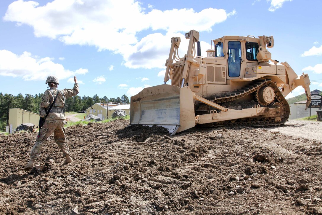 South Dakota Army National Guard Sgt. Kymberlee Hassebroek, left, directs Spc. Justin Barden, operating a D7 Dozer, where to go next in support of Golden Coyote, Lead, S.D., June 14, 2017. Hassebroek and Barden are assigned to the 842nd Engineer Company. Army photo by Spc. Jeffery Harris