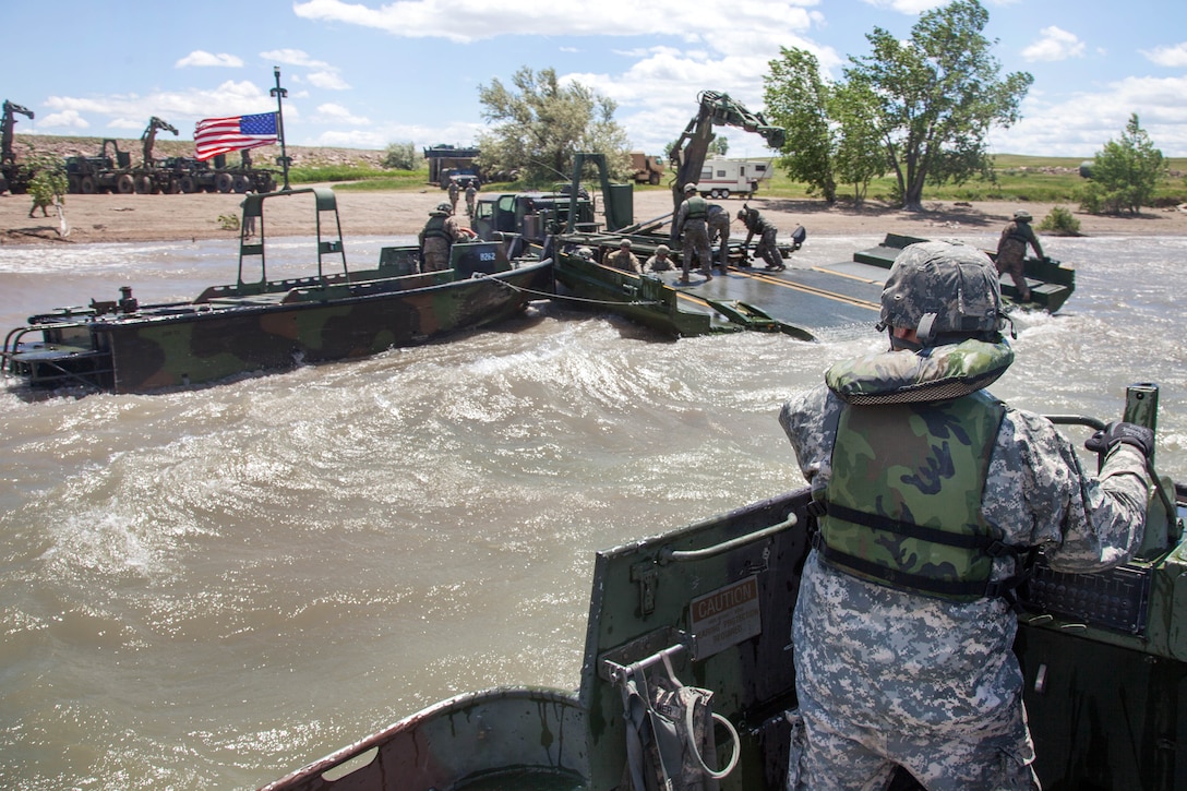 South Dakota Army National Guardsmen use an Mk2 bridge erection boat to move an Improved Ribbon Bridge out of the water during exercise Golden Coyote in Orman, S.D., June 14, 2017. Army photo by Spc. Jeffery Harris 