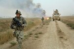 Soldiers assigned to Task Force 1-35 Armor, 2nd Brigade Combat Team, 1st Armored Division, make their way down road as canal burns in Tahwilla, Iraq, July 30, 2008 (U.S. Army/David J. Marshall)