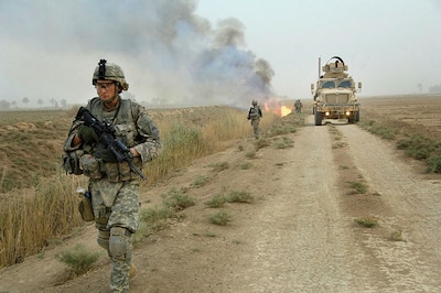 Soldiers assigned to Task Force 1-35 Armor, 2nd Brigade Combat Team, 1st Armored Division, make their way down road as canal burns in Tahwilla, Iraq, July 30, 2008 (U.S. Army/David J. Marshall)