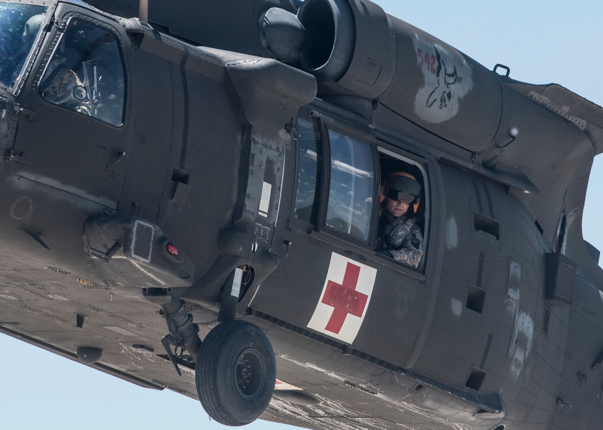 A U.S. Army member of the 6-101st Aviation Regiment from Fort Campbell, Kentucky leans out of the window of a UH-60 Black Hawk during their units first-ever medical water extraction with Survive, Evade, Resist and Escape instructors  Scott Air Force Base at Lake Carlyle, Illinois, June 7, 2017. Lt. Col. Brooke Matson, 375th Operations Support Squadron, Lt. Col. Brandon Dow, 54th Airlift Squadron, and Maj. Madison Basil Jr., Air Mobility Command, received hoist, water survival and flare training to learn how to survive in aqautic situations long enough to be rescued. The 101st Combat Aviation Brigade has served in almost every single military operation since the Vietnam War, including combat, peacekeeping, and humanitarian. By partnering with AMC's SERE instructors, this training allows for joint-service coordination while preparing aerial crew members to survive in austere locations ater being displaced from their aircraft. (U.S.Air Force photo by Airman 1st Class Daniel Garcia)