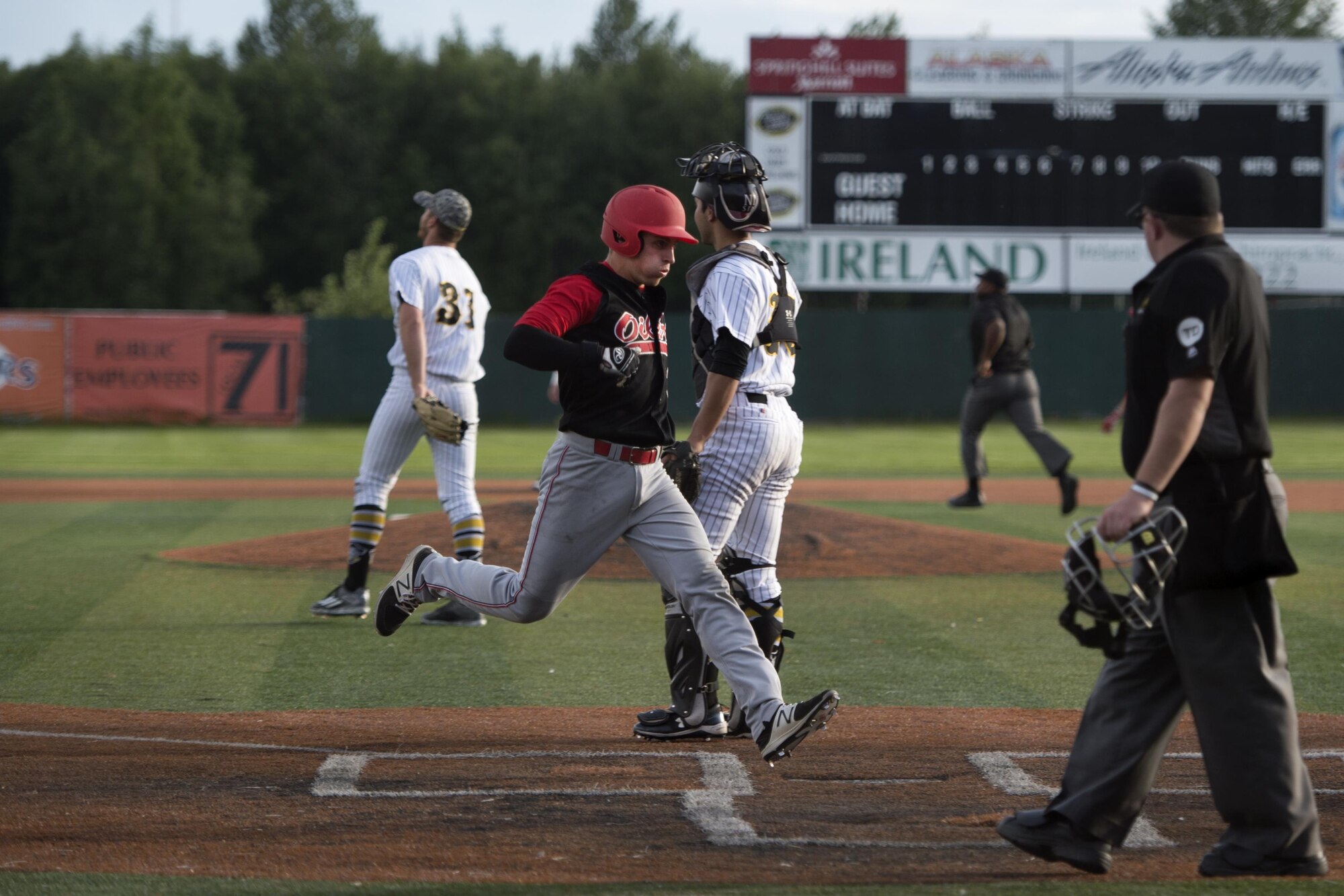 A Peninsula Oilers baseball player races home after a base hit at Mulcahy Stadium in Anchorage, Alaska, June 16, 2017. The Anchorage Bucs faced off against the Peninsula Oilers for a doubleheader as part of a military appreciation event.