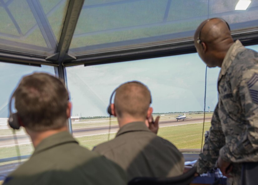 Col. Thomas Shank, 47th Flying Training Wing commander, Capt. Brandon Gaines-Richcreek, 47th Student Squadron instructor pilot, and Chief Master Sgt. Ronald Harper, 47th Mission Support Group superintendent (left to right), watch as the first aircraft in a four-ship formation takes off at Laughlin Air Force Base, June 16, 2017. Shank and Harper had an opportunity to take control in the Runway Supervisory Unit, giving the inbound and outbound aircraft instructions as they navigate the runway. (U.S. Air Force photo/Airman 1st Class Benjamin N. Valmoja)