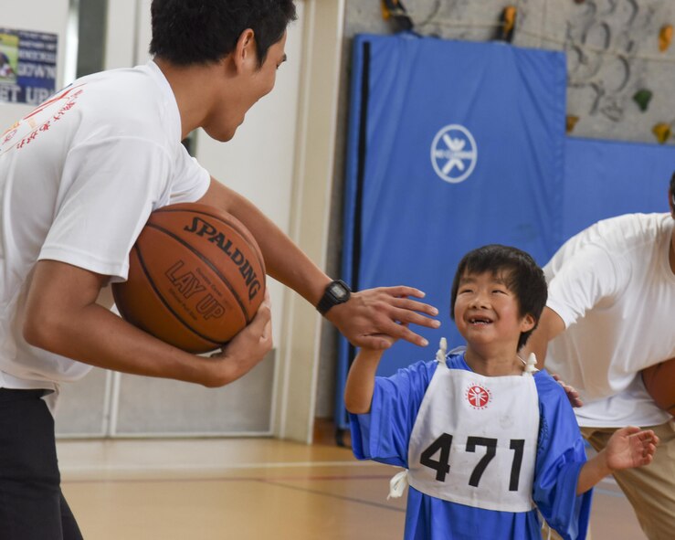 A competitor participating in the basketball exchanges a high-five with a volunteer during the 38th Annual Kanto Plains Special Olympics at Yokota Air Base, Japan, June 17, 2017. Approximately 1000 volunteers from United States Armed Forces, Japan Self-Defense Forces and local communities took part in the event and cheered on athletes. (U.S. Air Force photo by Machiko Arita)