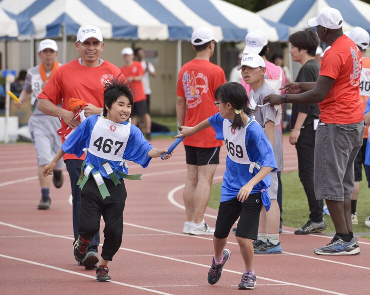 An athlete passes a sash to their relay teammate during the 38th Annual Kanto Plains Special Olympics at Yokota Air Base, Japan, June 17, 2017. 127 athletes from eight local schools and the Department of Defense Education Activity throughout the Kanto Plain region competed in various sports ranging from the track and field and bowling to basketball and swimming. (U.S. Air Force photo by Machiko Arita)