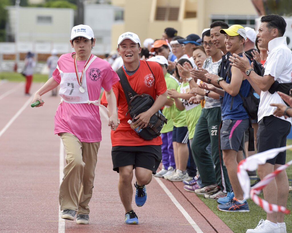 An athlete runs alongside a volunteer in the 400 meters relay during the 38th Annual Kanto Plains Special Olympics at Yokota Air Base, Japan, June 17, 2017. Each athlete was assigned a buddy from a volunteers to escort, keep company with, and cheer on their athlete throughout the event. (U.S. Air Force photo by Machiko Arita)