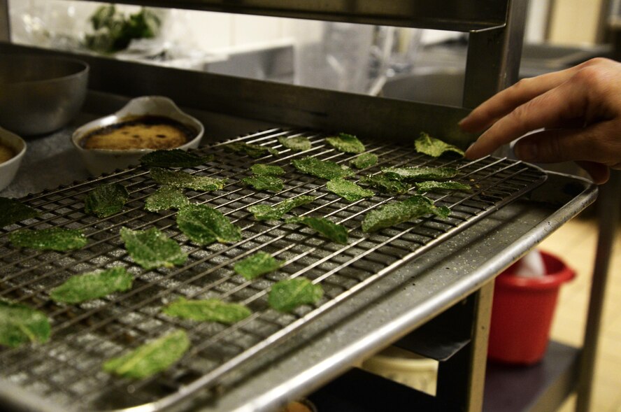 An Airman checks on candied mint leaves made during culinary training at the Gateway Dining Facility on RAF Mildenhall, England, June 8, 2017. Part of the weeklong training focused on encouraging creativity within the 100th Force Support Squadron members. Though cooks are required to follow a set menu, but they can add finesse and technique to food preparation. (U.S. Air Force photo by Senior Airman Justine Rho) 