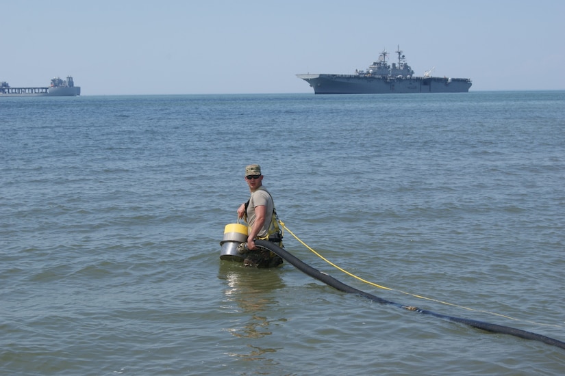 Spc. Jose Villareal, with the 753rd Composite Supply Company water purification team, carries equipment into the Atlantic Ocean to extract salt water as part of the Reverse Osmosis Water Purification Rodeo at Fort Story, Virginia, June 12, 2017.