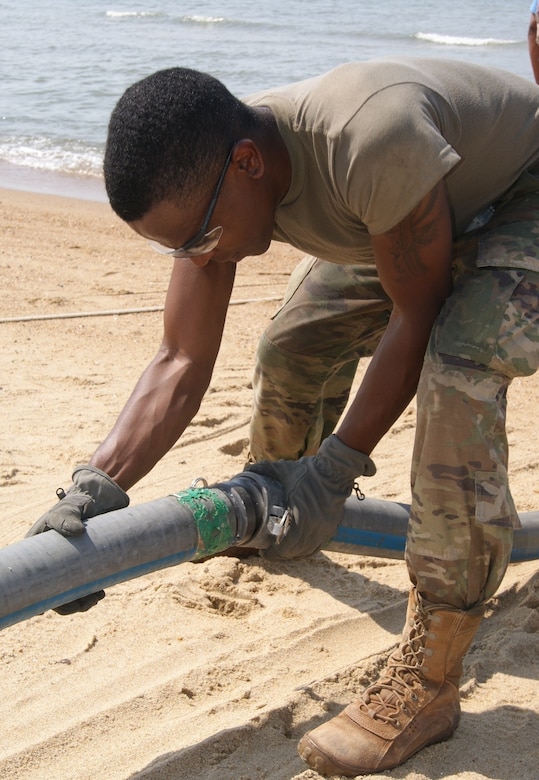 Spc. Donovan Stutts, member of the 40th Composite Supply Company water purification team, secures pipes together to pump salt water during the Reverse Osmosis Water Purification Unit Rodeo at Fort Story, Virginia, June 12, 2017.
