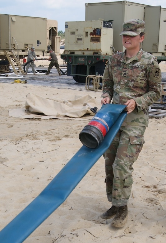 Private 1st Class Kayla Jacobs, member of the 249th Composite Supply Company water purification team, straightens a water hose during the Reverse Osmosis Water Purification Unit Rodeo at Fort Story, Virginia, June 13, 2017.