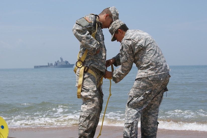 (Right) Sgt. Miriam Gallardo helps Spc. Javier Ramirez, both on the 961st Quartermaster Company water purification team, to prepare for entering the Atlantic Ocean as part of the Reverse Osmosis Water Purification Unit Rodeo at Fort Story, Virginia, June 13, 2017.