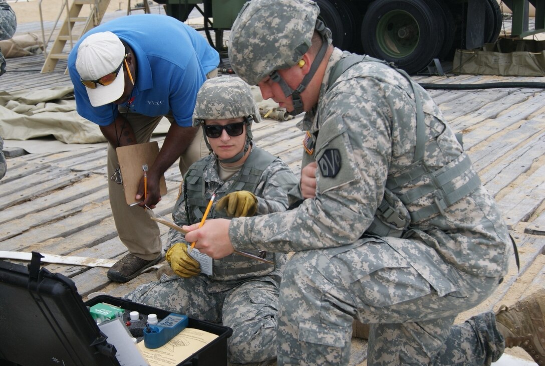 (Kneeling left to right) Spc. Brandi Madden and Spc. Scott Morin, members of the 125th Quartermaster Company water purification team, test salt water as a Forces Command Logistics Training Cluster evaluator assesses them at the Reverse Osmosis Water Purification Unit Rodeo at Fort Story, Virginia, June 15, 2017.
