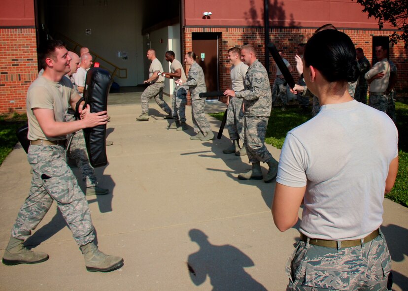 In the foreground, Staff Sgt. Nicole Frost shouts out staging instructions to 932nd Security Forces Squadron members.  They used their protective shields (left) to brace for impact from pressure applied by fellow squadron member (at right), during a baton blocking training class, at Scott Air Force Base, Illinois, June 4, 2017.   Several airmen later volunteered to be in the  padded RedMan suit to better appreciate the mission and training of the 932nd AW SFS team. It was all about training, unit bonding, and outdoor crowd control and aggressor experience.  (U.S. Air Force photo by Lt. Col. Stan Paregien)