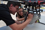 DAHLGREN, Va. (June 15, 2017) - Navy scientist Charles Miller and mathematician Jessica Hildebrand perform pre-flight checks on the SCAPEGOAT chemical, biological, and radiological (CBR) detection system. The SCAPEGOAT system - developed by a team of Naval Surface Warfare Center Dahlgren Division junior scientists and engineers - demonstrates the capability to deploy a modular CBR sensor system aboard multiple unmanned aerial vehicle platforms.