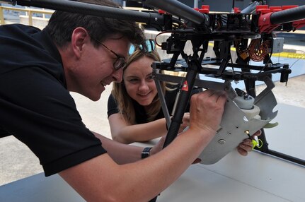 DAHLGREN, Va. (June 15, 2017) - Navy scientist Charles Miller and mathematician Jessica Hildebrand perform pre-flight checks on the SCAPEGOAT chemical, biological, and radiological (CBR) detection system. The SCAPEGOAT system - developed by a team of Naval Surface Warfare Center Dahlgren Division junior scientists and engineers - demonstrates the capability to deploy a modular CBR sensor system aboard multiple unmanned aerial vehicle platforms.