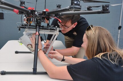 DAHLGREN, Va. (June 15, 2017) - Navy scientist Charles Miller and mathematician Jessica Hildebrand perform pre-flight checks on the SCAPEGOAT chemical, biological, and radiological (CBR) detection system. The SCAPEGOAT system - developed by a team of Naval Surface Warfare Center Dahlgren Division junior scientists and engineers - demonstrates the capability to deploy a modular CBR sensor system aboard multiple unmanned aerial vehicle platforms.