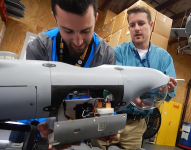 DAHLGREN, Va. (June 15, 2017) - Navy scientist Jordan Lieberman, left, works with engineer Jonathan Crook to install the SCAPEGOAT payload onto a Boeing Insitu Scan Eagle unmanned aerial vehicle (UAV) prior to a system test flight. The SCAPEGOAT system - which includes modular interfaces to multiple chemical, biological, and radiological sensors and UAV platforms - was developed by junior scientists and engineers engaged in the Naval Surface Warfare Center Dahlgren Division sponsored Sly Fox Program over a six-month period.