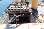 The forward ships crane on the M/V Ocean Jazz lifts an Apache helicopter into the hold during port operations at Pearl Harbor on June 12.  