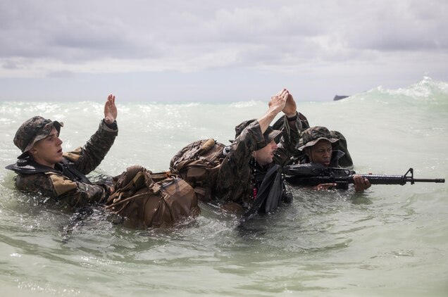 MARINE CORPS TRAINING AREA BELLOWS - Lance Cpl. Shane Springstead, Cpl. Ryan Ehlers, and Lance Cpl. Armanie Singletary, radio reconnaissance team operators with Radio Reconnaissance Platoon, 3rd Radio Battalion give the “far okay” signal to team members on the beach during the Radio Reconnaissance Operator Course aboard Marine Corps Training Area Bellows, June 15, 2017. The signal indicates that there were no casualties during the team’s insertion. (U.S. Marine Corps photo by Lance Cpl. Luke Kuennen)
