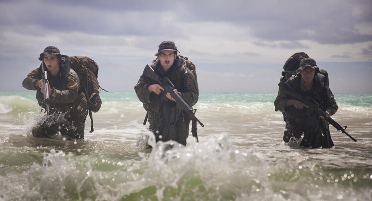 MARINE CORPS TRAINING AREA BELLOWS - Lance Cpl. Shane Springstead, Cpl. Ryan Ehlers, and Lance Cpl. Armanie Singletary, radio reconnaissance team operators with Radio Reconnaissance Platoon, 3rd Radio Battalion prepare to take the beach by force during the Radio Reconnaissance Operator Course aboard Marine Corps Training Area Bellows, June 15, 2017. To reach the shore, Marines had to complete a two kilometer swim with more than 65 pounds of gear. (U.S. Marine Corps photo by Lance Cpl. Luke Kuennen)