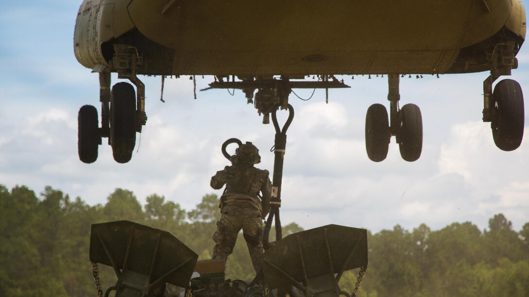 An Army artilleryman hooks up an M777 howitzer to a CH-47 Chinook during Exportable Combat Training Capability Rotation 17-04, a three-week training exercise at Fort Stewart, Ga., June 19, 2017. Army photo by Staff Sgt. Nikki Felton