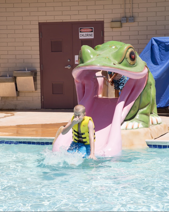 Dakoda Hainer splashes down off of the frog slide at the Oasis Pool and Water Park during School Age Care Summer Camp held aboard Marine Corps Logistics Base Barstow, Calif., June 15.