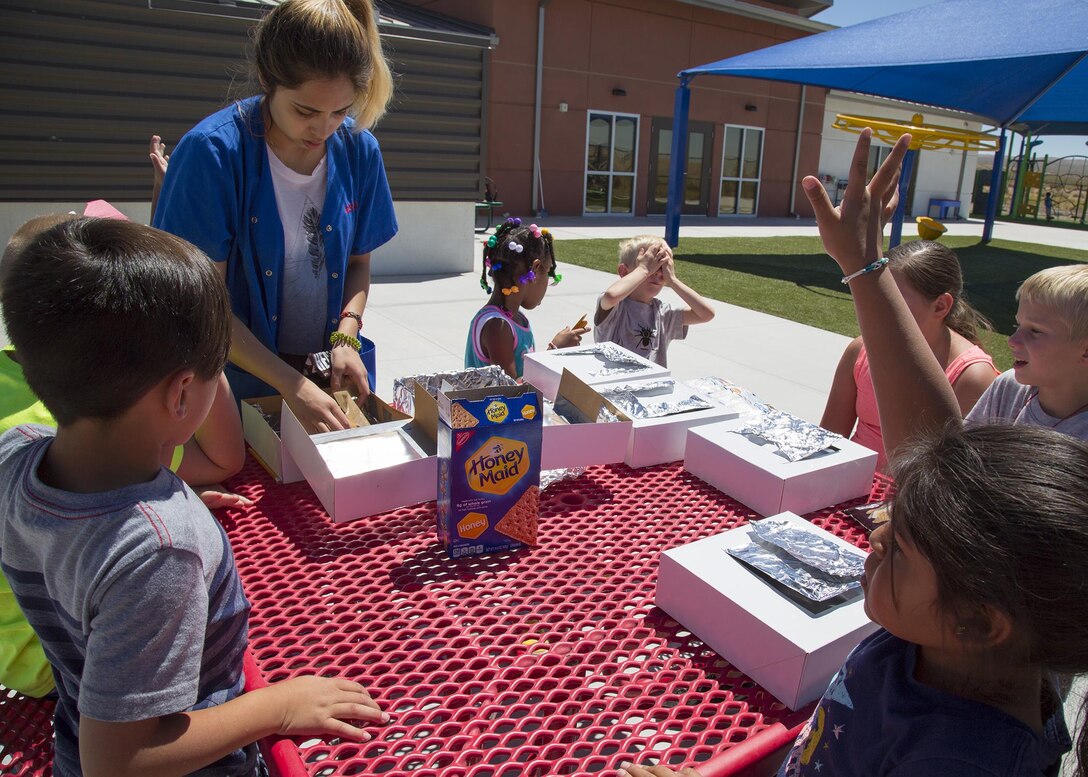 Genesis Delgado, child youth provider for School Age Care, shows children how to make S'mores using a solar oven they made during an arts and crafts session earlier in the week, during their Summer Camp festivities, held aboard Marine Corps Logistics Base Barstow, Calif., June 14.