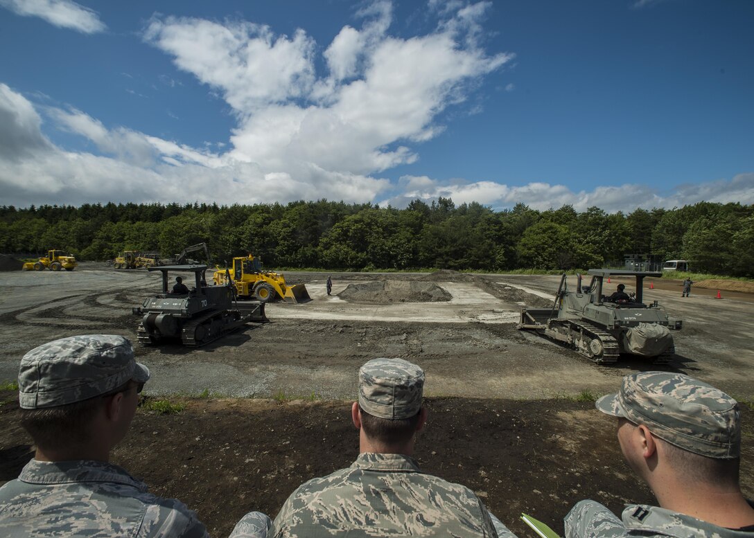 Airmen from the 35th Civil Engineer Squadron observe a Japan Air Self-Defense Force rapid runway repair exhibition during a bilateral exchange event at Misawa Air Base, Japan, June 22, 2017. This is phase one of a RRR, which fills in a crater or hole with gravel. The exchange focused on base recovery, which ensures infrastructure and airfields remain operational if a natural disaster or an attack occurs. (U.S. Air Force photo by Senior Airman Deana Heitzman)