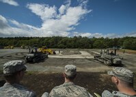 Airmen from the 35th Civil Engineer Squadron observe a Japan Air Self-Defense Force rapid runway repair exhibition during a bilateral exchange event at Misawa Air Base, Japan, June 22, 2017. This is phase one of a RRR, which fills in a crater or hole with gravel. The exchange focused on base recovery, which ensures infrastructure and airfields remain operational if a natural disaster or an attack occurs. (U.S. Air Force photo by Senior Airman Deana Heitzman)
