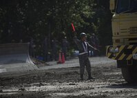 A Japan Air Self-Defense Force civil engineer Airman signals a construction truck during a rapid runway repair exhibition at Misawa Air Base, Japan, June 22, 2017. In addition to the RRR exhibition, CE Airmen from both countries learned about each other’s mission sets and watched live-fire and emergency management demonstrations. (U.S. Air Force photo by Senior Airman Deana Heitzman)