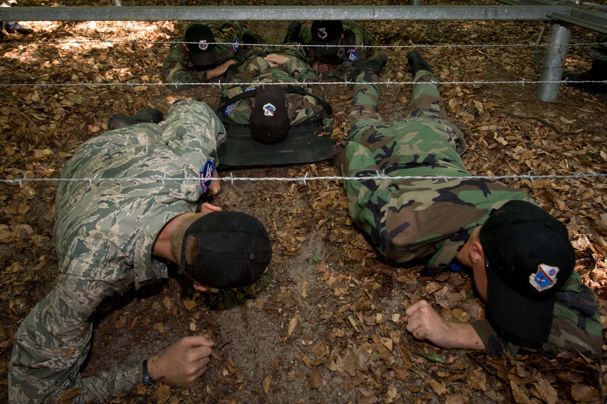 Cadets with the Civil Air Patrol European Encampment pull a simulated patient under barbed wire on a woodland obstacle course on Ramstein Air Base, Germany, June 21, 2017. The encampment curriculum encompasses four core areas: aerospace education, leadership development, character development, and physical fitness. The curriculum designed, in part, to prepare cadets for a possible military aerospace career. (U.S. Air Force photo by Senior Airman Elizabeth Baker)