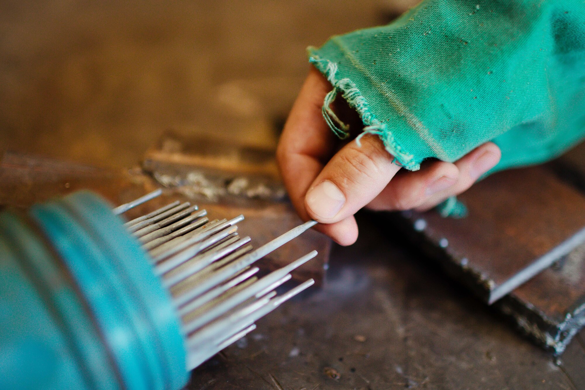 Airman 1st Class Hogan Lambeth, 11th Civil Engineer Squadron structural apprentice, grabs a metal rod to weld at Joint Base Andrews, Md., June 21, 2017. As a metals structural technician, Lambeth is called on to complete welding, sheet metal, duct work, fabrication and repairs to maintain equipment and facilities throughout the base. (U.S. Air Force photo by Senior Airman Delano Scott)