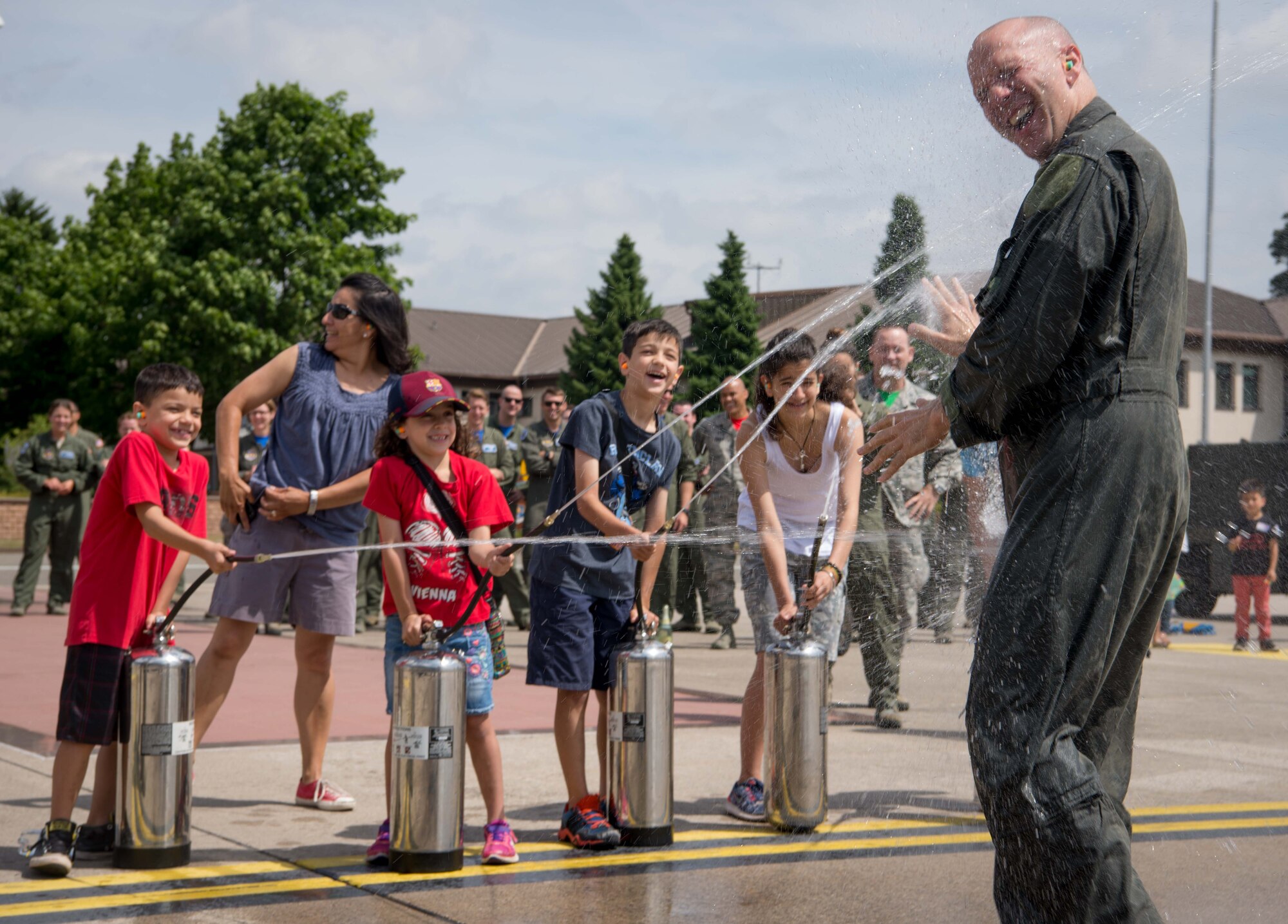 Col. Gerald Donohue, 86th Operations Group commander, laughs as his family sprays him with water at Ramstein Air Base, Germany, June 23, 2017. Donohue participated in the Air Force tradition of a final flight, or "fini" flight, in which a transitioning aircrew member performs his final flight, and then friends and family greet and spray him down. (U.S. Air Force photo by Senior Airman Elizabeth Baker)