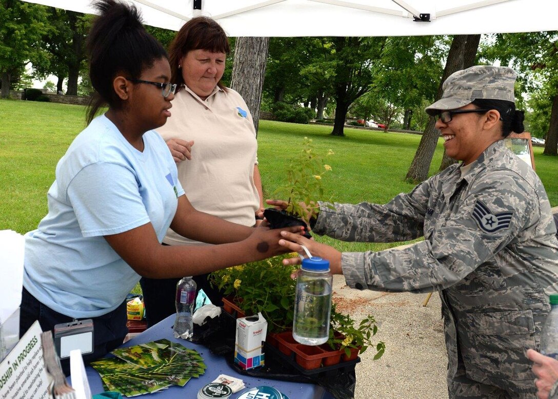 Raejean Smith, Five River Metro Parks volunteer, gives a Lantana plant to Staff Sgt. Cassandra Mena, United States Air Force School ofAerospace Medicine industrial hygiene laboratory technician, during the Pollinator Expo held at the Wright Brothers Memorial located outside Wright-Patterson Air Force BaseJune 21. Numerous local organizations were on site to highlight the work they do to protect pollinators and their habitats.(U.S.Air Force photo/Michelle Gigante)