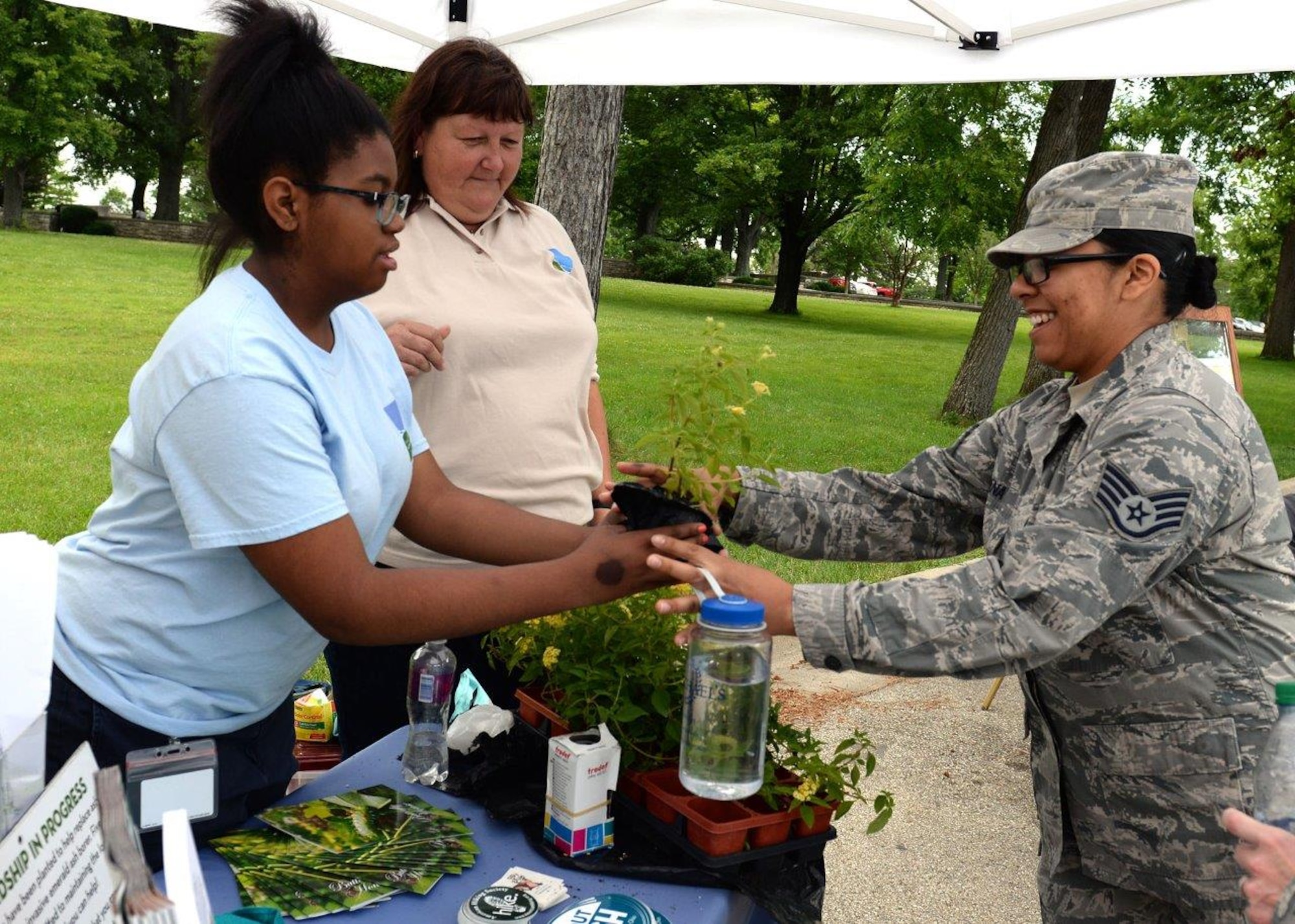 Raejean Smith, Five River Metro Parks volunteer, gives a Lantana plant to Staff Sgt. Cassandra Mena, United States Air Force School ofAerospace Medicine industrial hygiene laboratory technician, during the Pollinator Expo held at the Wright Brothers Memorial located outside Wright-Patterson Air Force BaseJune 21. Numerous local organizations were on site to highlight the work they do to protect pollinators and their habitats.(U.S.Air Force photo/Michelle Gigante)