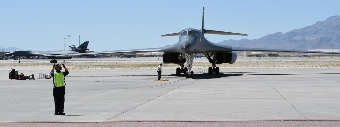 A B-1B Lancer parks, while another taxis down the runway during weapons integration at Nellis Air Force Base, Nev., June 14, 2017. In the final week of integration, the mission takes four days to review, prepare, plan and execute. To complete this three hour mission, 40 hours is invested by each participant. (U.S. Air Force photo by Senior Airman Shannon Hall) 
