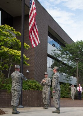 Senior Airman Alec Cope, center, and Tech. Sgts. Paul Cram, left, and Richard Leger, members of the Patriot Honor Guard team, retrieve the flag as the national anthem is played during a retreat ceremony outside the Brown Building at Hanscom Air Force Base, Mass., June 22. Retreat is played to mark the end of the duty day and precedes the playing of the national anthem. (U.S. Air Force photo by Mark Herlihy)
